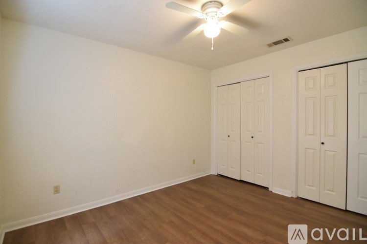 A room with a ceiling fan and wooden flooring.