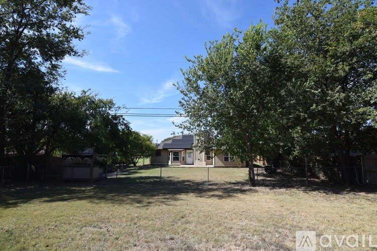 A house is surrounded by trees and grass in the foreground.