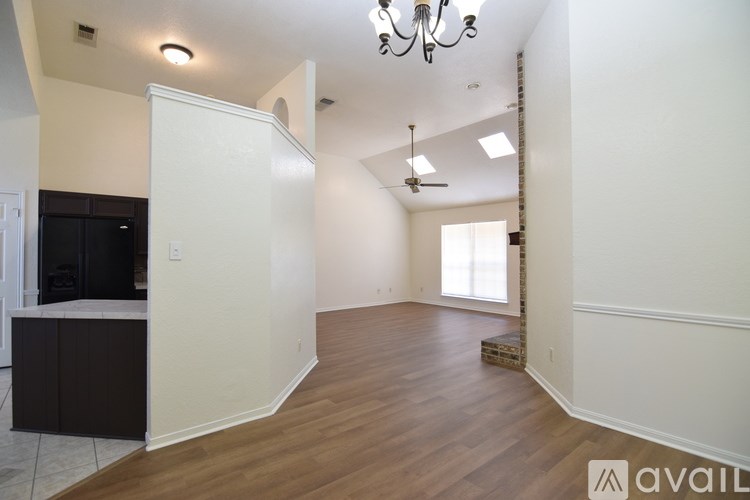 A spacious living room with a chandelier and hardwood floors.