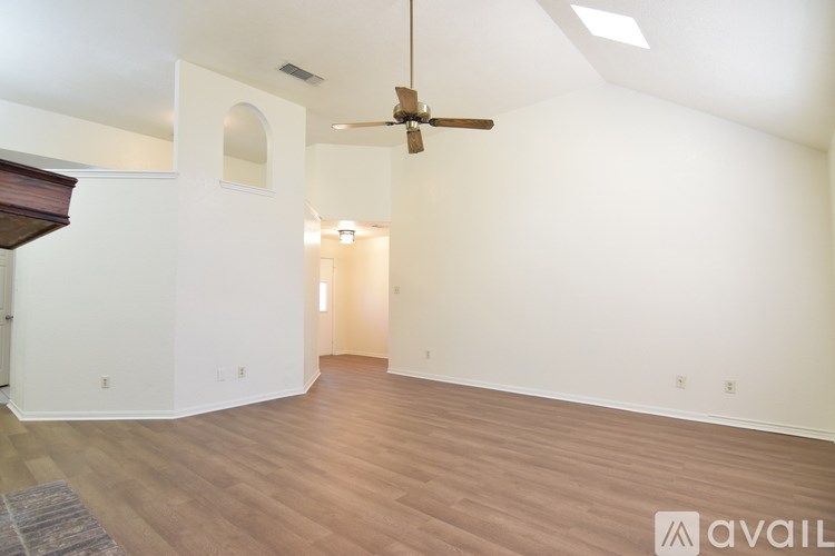 A spacious room with a ceiling fan and hardwood flooring.