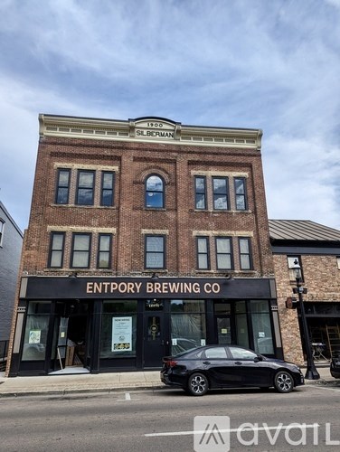 A black car is parked in front of a building with a sign that says "Entropy Brewing Co.".