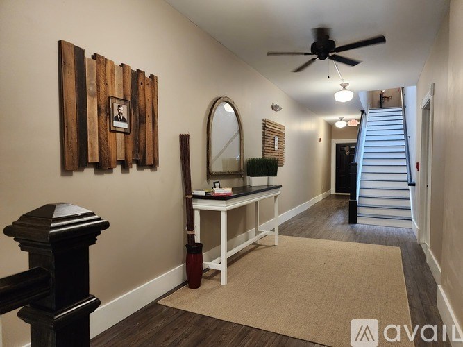 A hallway with a mirror, a table, and a wooden picture frame on the wall.