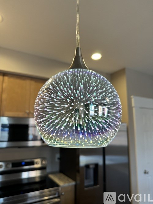 A chandelier with a starburst design is hanging from the ceiling in a kitchen.