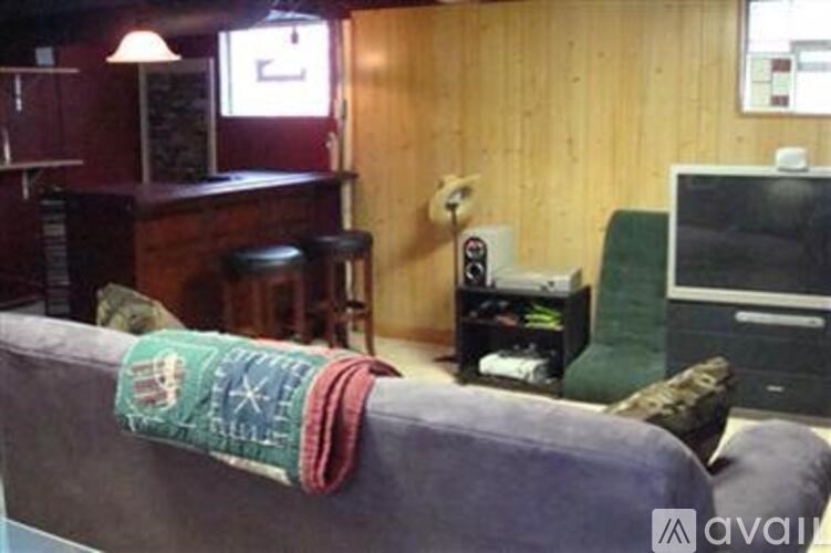 A room with a couch, a bar, and a television.