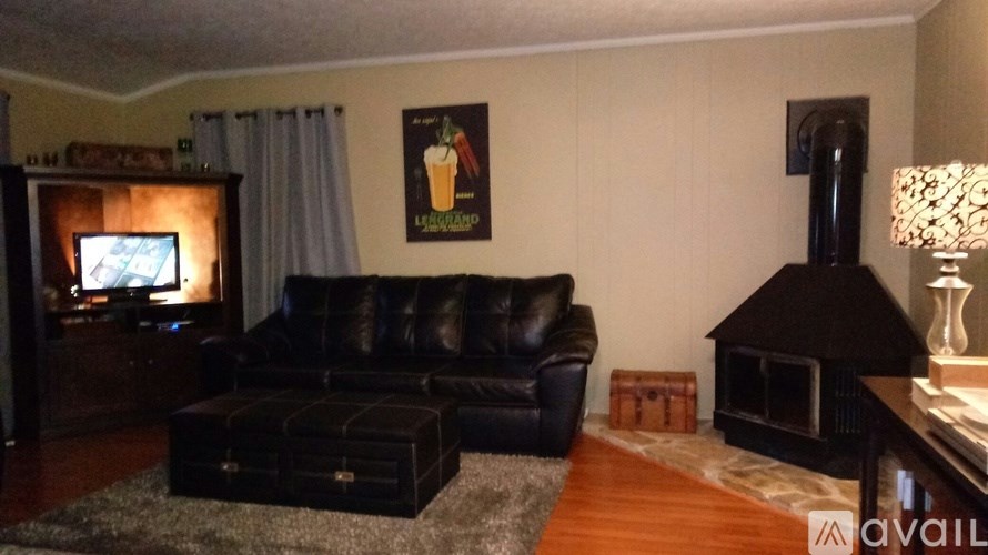 A living room with a black leather couch and a television on a wooden cabinet.