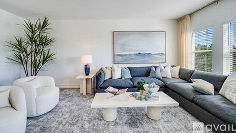 A living room with a grey couch, a white armchair, a white coffee table, and a painting on the wall.