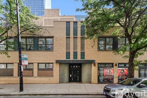 A building with a black door and windows with trees in front.