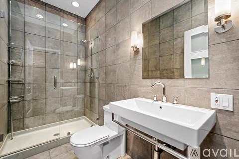A modern bathroom with a glass shower stall and a white sink.
