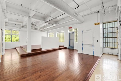 A large empty room with wooden floors and white walls.
