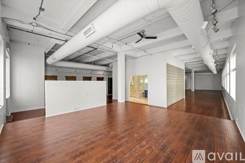 A spacious room with wooden floors and white walls.