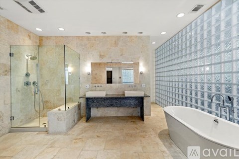 A bathroom with a glass shower, a bathtub, and a marble countertop.