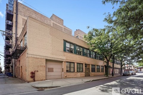 A large brick building with a garage door and a tree in front.