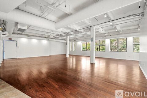 A spacious room with wooden floors and white walls.