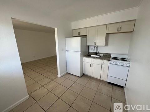 A kitchen with white appliances and beige tiles.