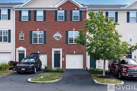 A brick building with a black car and a red truck parked in front.