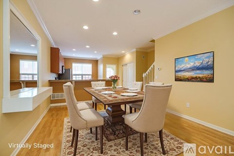 A dining room with a table set for four and a painting on the wall.