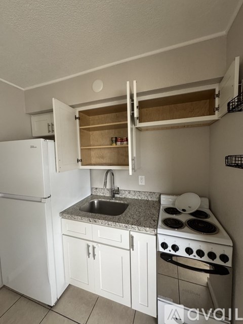 A small kitchen with a white refrigerator, a white stove, and a white sink.