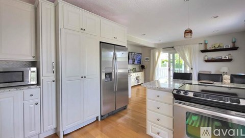 A kitchen with white cabinets and a stainless steel refrigerator.