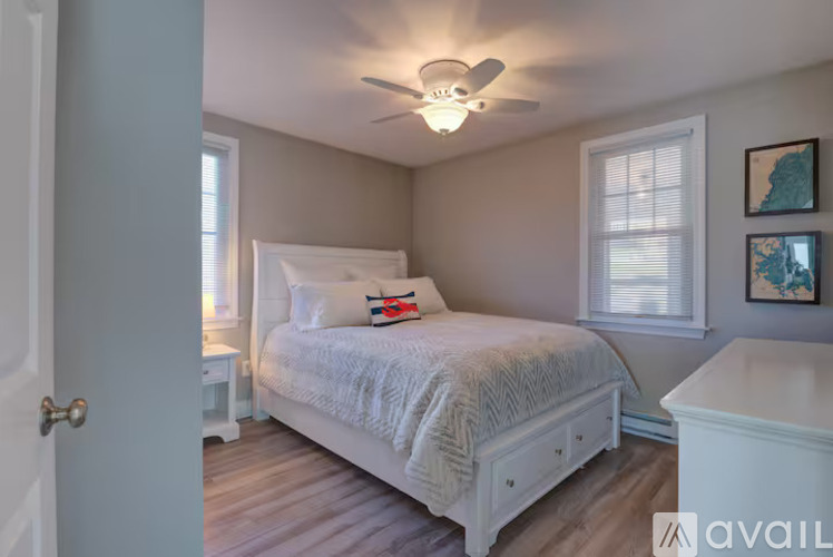 A bedroom with a white bed and a ceiling fan.