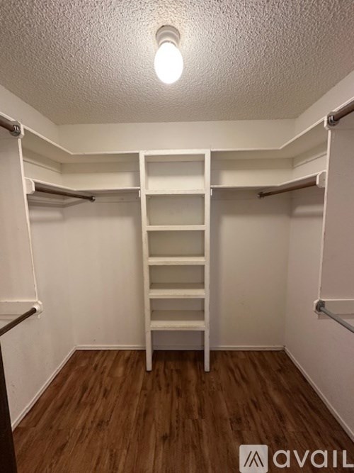 A white closet with a wooden floor and a light on the ceiling.
