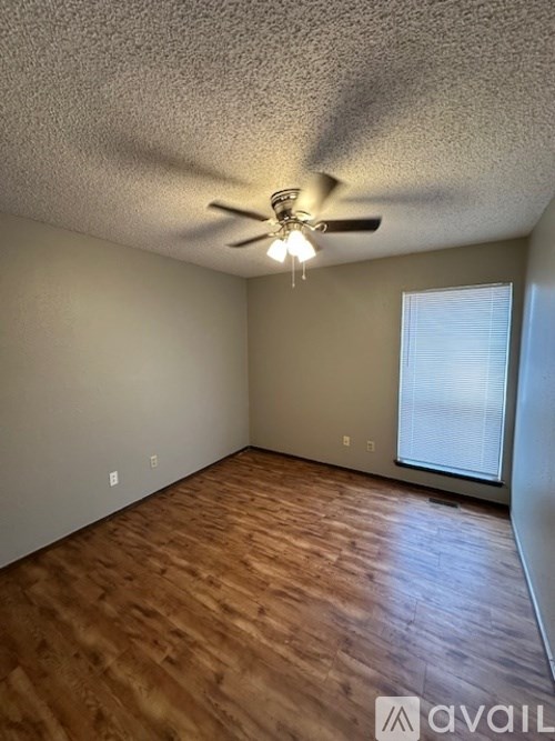 A room with a ceiling fan and wooden flooring.