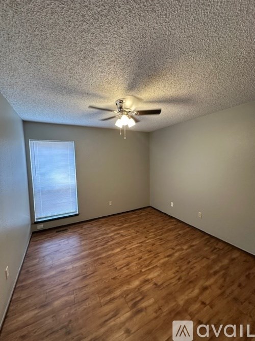 A room with a ceiling fan and wooden flooring.
