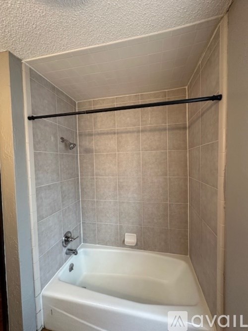 A bathroom with a white tub and a black grab bar.