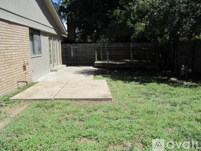 A backyard with a concrete slab and a fence.