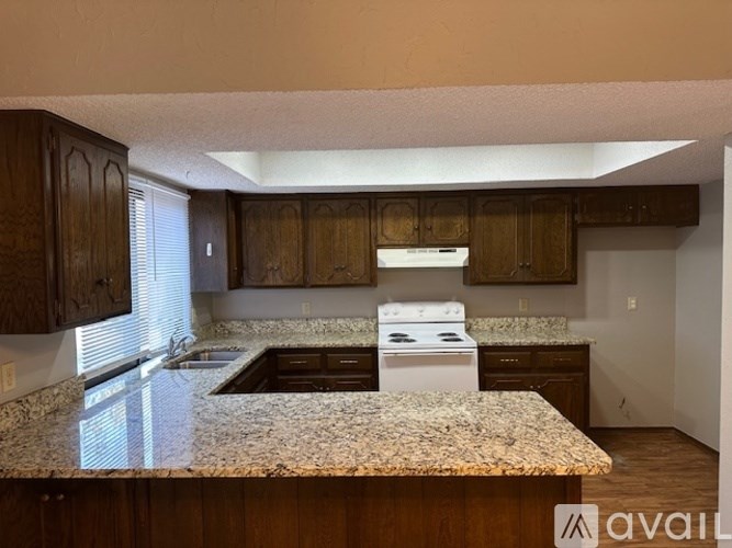 A kitchen with granite countertops and wooden cabinets.