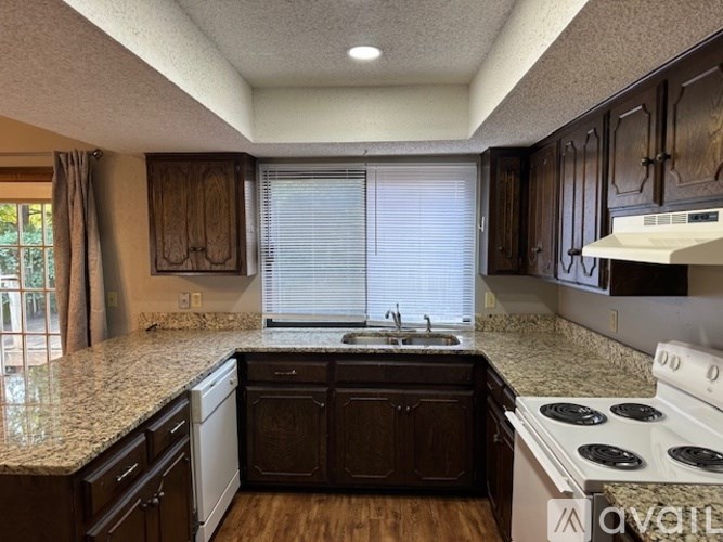 A kitchen with dark wood cabinets and a granite countertop.
