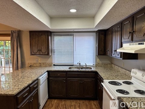 A kitchen with dark wood cabinets and a granite countertop.
