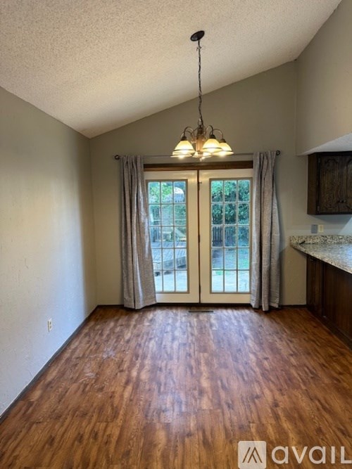 A room with wooden floors and a large window with curtains.