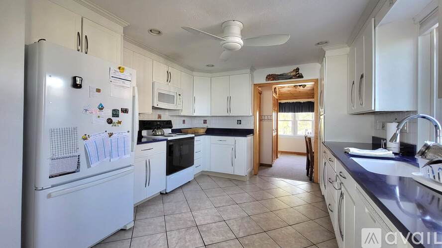 A kitchen with white cabinets and a white fridge.