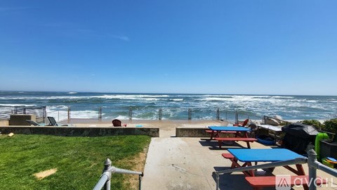 A beachside picnic area with tables and chairs overlooking the ocean.