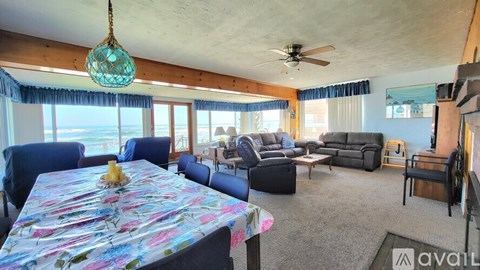 A living room with a dining table set up with a floral tablecloth and a hanging glass chandelier.