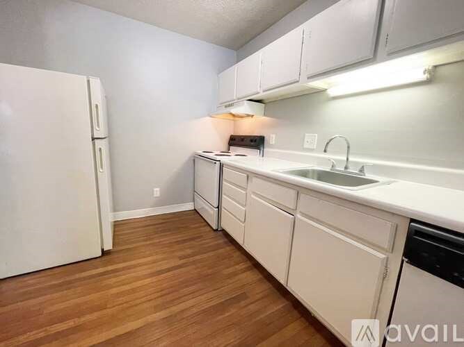 A kitchen with white cabinets and a white fridge.