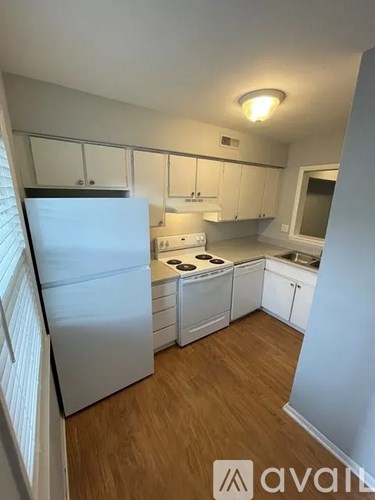 A kitchen with white appliances and wooden floors.