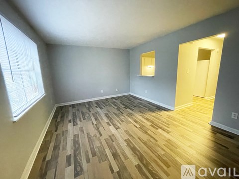 A room with wooden flooring and a window on the left side.