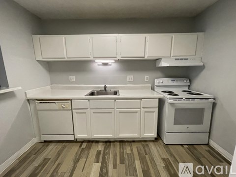 A kitchen with white cabinets and a wooden floor.