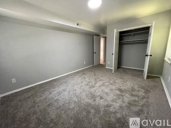 A spacious room with grey carpeting and a door on the right.