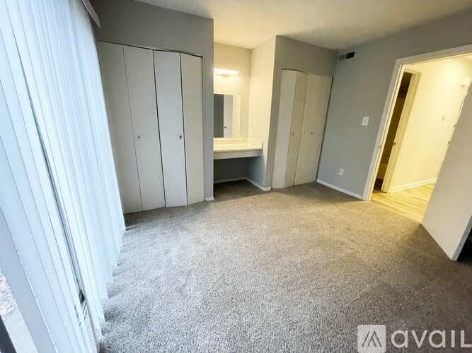 A bedroom with a carpeted floor and a white wardrobe.