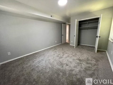 A spacious room with grey carpeting and a door on the right.