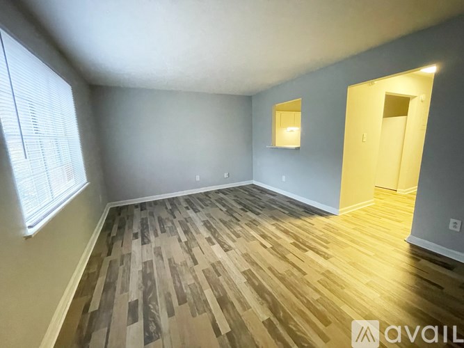 A room with wooden flooring and a window on the left side.