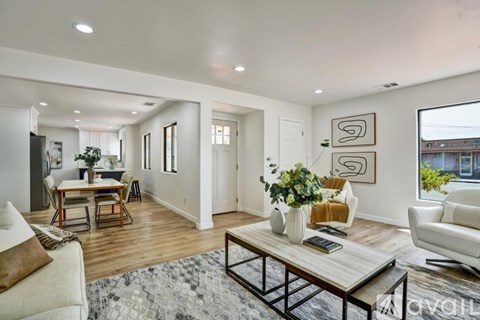 A modern living room with a white sofa, a wooden coffee table, and a large window.