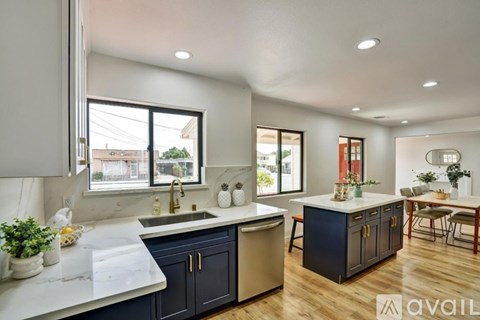 A modern kitchen with dark blue cabinets and a white countertop.