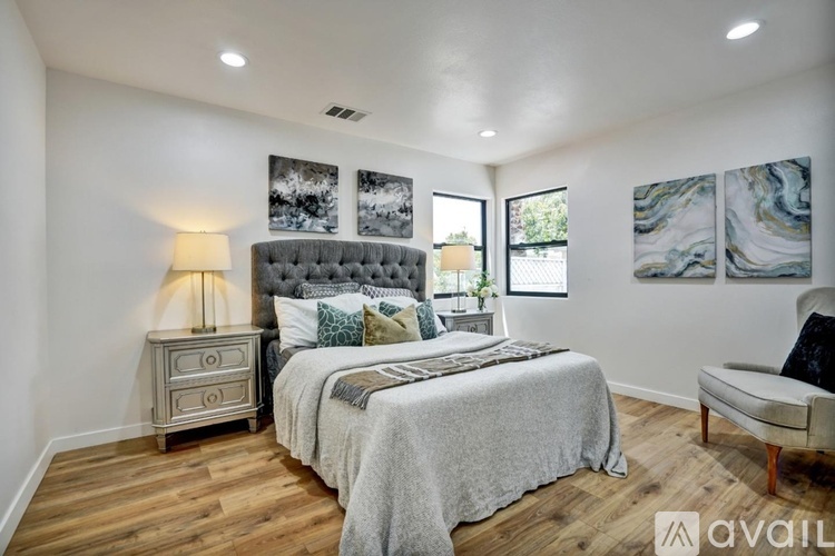 A bedroom with a large bed, a nightstand with a lamp, and a chair.