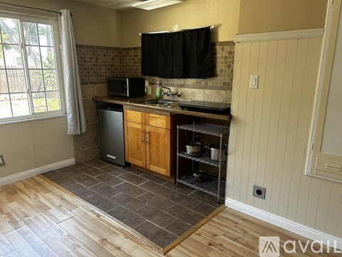 A kitchen with wooden cabinets and a black microwave.