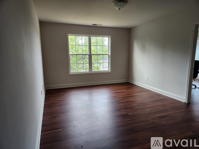 A room with wooden floors and a window letting in natural light.