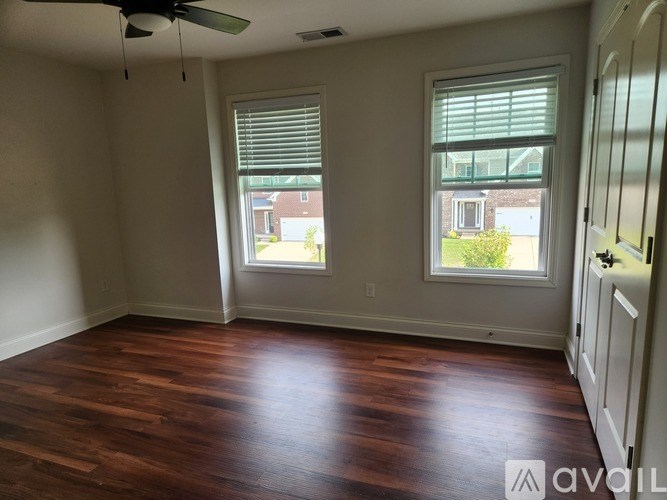 A room with wooden floors and two windows.