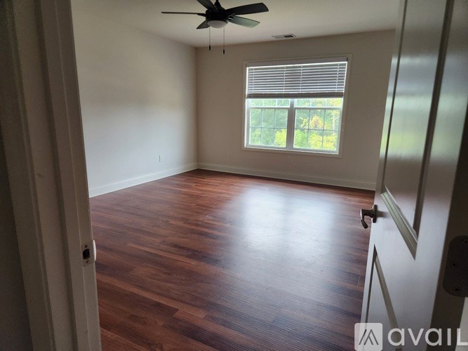 A room with a ceiling fan and a window with blinds.